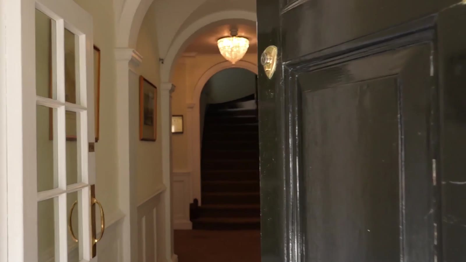 The black front door of 1 Buckingham Place, open onto the entrance hall and staircase