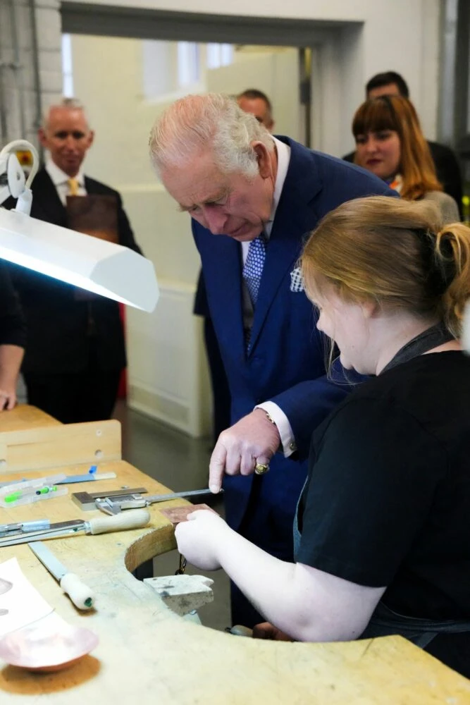 His Majesty The King watching a young goldsmith at the bench during a visit to the Goldsmiths&rsquo; Centre